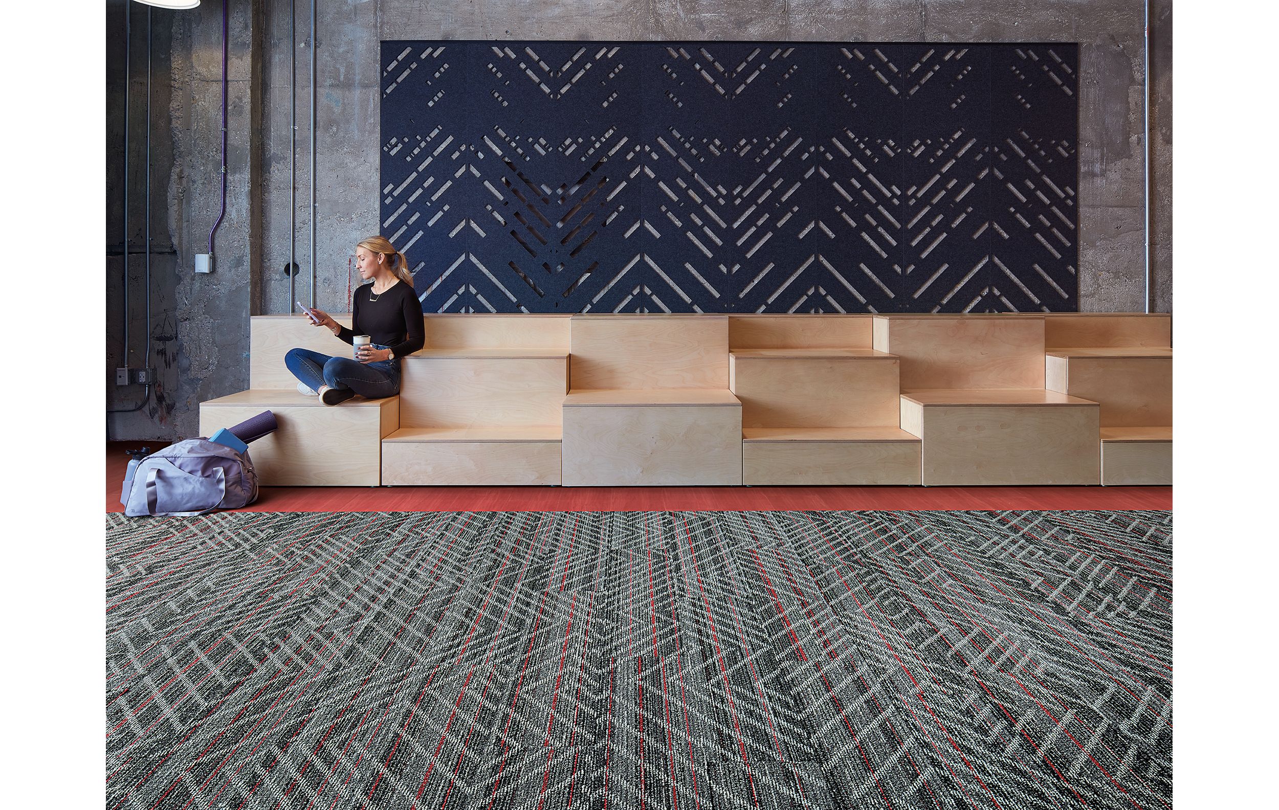 Interface Reflectors plank carpet tile with Studio Set LVT in open area with woman seated on wood risers imagen número 2